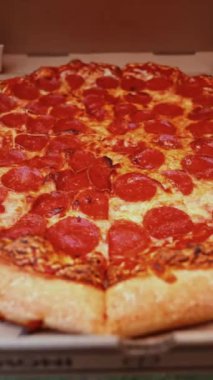 Bir arka bahçede pepperonili pizza kutusu açılıyor ve Bağımsızlık Günü kutlamaları için mükemmel dilimler çıkıyor.