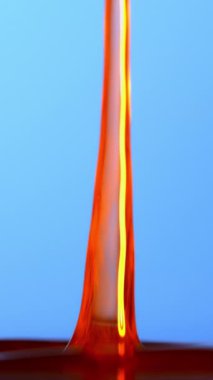 Canlı turuncu ve sarı damlacıklar zarif bir şekilde mavi bir zemine düşerler, renkli ve hareketli hoş bir görsel görüntü oluştururlar.