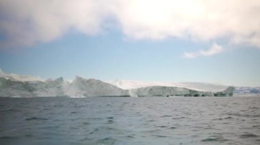 Grönland Arktik sularında zarif bir şekilde sürüklenen buzdağları sakin ve görkemli bir manzara yakalıyor.
