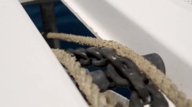 Yakın çekim, bir teknede birbirine dolanmış kalın metal zincirler ve halatlar yakalar. Yıpranmış ve yıpranmış halatların yanında birbirine kenetlenmiş halkalar ve güçlü zincirler sergiler.