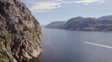 Sakin sularda süzülen ve görkemli çayırlarda gezinirken zarif su izleri bırakan bir teknenin hava görüntüsü.