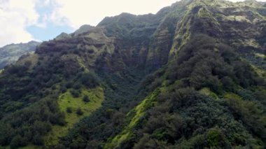 Marquesas Adaları 'nın verimli dağlarından gün boyunca çekilen insansız hava aracı açık mavi gökyüzüne karşı canlı yeşillikleri ve engebeli araziyi gözler önüne seriyor.