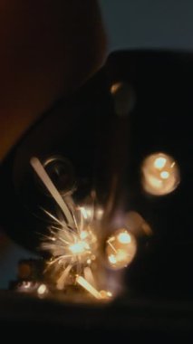 Yakın çekim, yavaş çekim, parlak kıvılcımlar saçan parlak bir kıvılcım ve parlak detaylarla parlayan bir alevin dramatik ateşini yakalıyor.