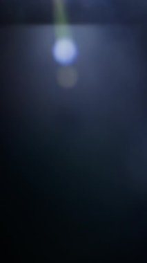 Parlak mercek parlıyor, parlak ışık ve yumuşak sinematik ışıltıyla karanlık bir arkaplanı aydınlatıyor.