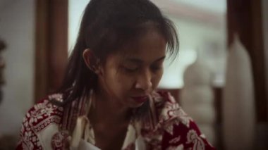 Seramik sanatçısı arka planda bulanık çömlek parçaları olan bir stüdyoda çömlek yapmaya odaklanmış.