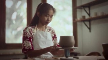 Zanaatkar çömlekçinin çarkındaki çömlek şeklini dikkatlice inceleyerek biçimini ve simetrisini ölçüyor.