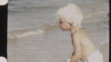 Odaklanmış bir çocuğun balık oltasına takılıp okyanus dalgalarının zemininde dikilirken çekilmiş eski bir fotoğrafı.