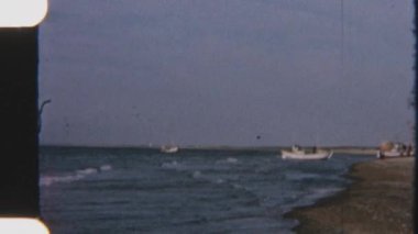 Sakin dalgalar yavaşça dalgalanırken sahilde dinlenen balıkçı tekneleri huzurlu bir sahil manzarası yaratıyor.