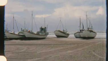 Kıyıda dizilmiş yelkenliler, bulutlu bir gökyüzünün altında dalgalarla yavaşça sallanıyorlar.
