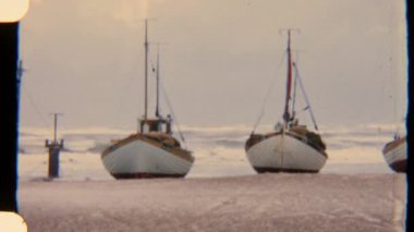 Sakin bir kumsalda dinlenen yelkenli sahnesi yumuşak dalgalar geliyor ve dramatik bulutlar tepemizde.
