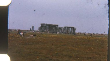 Turistlerin geniş yeşil alanları keşfettikleri klasik tarzda görüntüler. Arka planda ikonehenge sütunları var. Bu tarihi anıtın zamansız cazibesini yakalıyorlar.