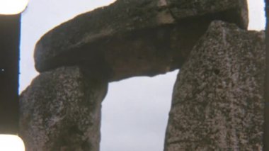 Stonehenge 'in klasik tarzda düşük açılı çekimi. Açık gökyüzüne doğru yükselen devasa taş sütunlar antik görkemi ve anıtın ebedi varlığını yansıtıyor.