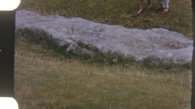 İki gezgin, yemyeşil otlaklarla çevrili düz taş patikalar boyunca sakin bir şekilde yürürler, huzurlu bir yolculuğun tadını çıkarırlar.