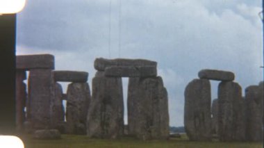 Antik Stonehenge, üzerinde bulutlu gökyüzü olan engin otlakların üzerinde dimdik duruyor. Bu ikonik anıtın ebedi güzelliğini yakalıyor.
