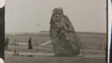 Stonehenge 'deki antik Sarsen Taşları' nın yanından geçen turistlerin tek renkli görüntüleri anıtın ölçeklerini ve tarihini vurguluyor.