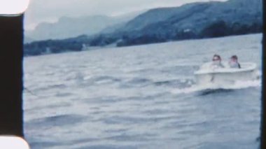 Bir anne ve oğul, sakin göl sularını, nefes kesici dağ manzaralarıyla çevrili bir teknede, 8 mm 'lik filmle keşfediyor.