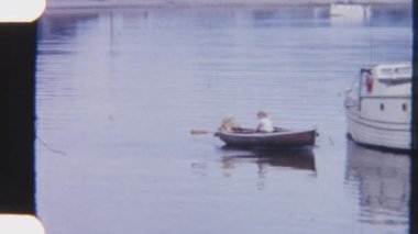 8 mm 'lik bir kanocu, sakin, güneşli sularda zarifçe süzülürken ince tekneyi kıyıdaki bir dinlenme teknesine yönlendirir ve arkalarında hafif dalgalar bırakır.