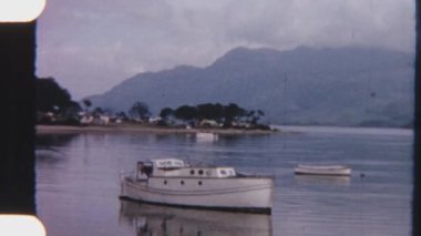 8 mm 'lik huzurlu bir sahne. Küçük bir tekne ve gösterişli bir kano, dağların nefes kesici manzarasına karşı kıyıda sessizce dinleniyor.