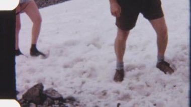 Kaşifler kayalık dağların karlı arazisinde yürürken, 8 mm 'lik bir filme çekilip engebeli yabanı gözler önüne seriyorlar.