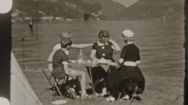 Dört kişilik bir aile gölün kenarında huzurlu bir pikniğin keyfini çıkarırken, arka planda muhteşem dağ manzarası olan 8 mm 'lik nostaljik bir filme çekiliyor.
