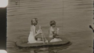 Kardeşler, doğa tarafından çevrelenmiş, sakin bir gölde 8 mm 'lik nostaljik bir filmle yakalanmış, şişme bir teknede kürek çekerler.