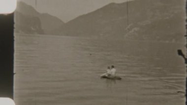 Baba ve oğul, 8mm 'lik nostaljik bir filme çekilen çarpıcı dağ manzarasıyla çevrili şişme bir teknede huzurlu bir gezinti yapıyorlar.