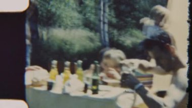 8mm 'lik klasik bir film, bir aileyi, yemyeşil yemyeşil çadırlarıyla çevrili piknik masasında yemek yerken yakalar ve doğanın kalbinde sıcacık ve unutulmaz bir an yaratır.