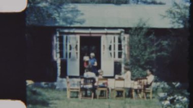 Mutlu bir aile güneşli bir günde arka bahçelerinde birlikte güzel vakit geçirir, arka planda evleri olan açık bir yemek seti etrafında toplanır, rahatlatıcı ve kalıcı anılar yaratır, 8 mm 'lik bir filme çekilir.