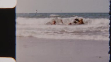 Mutlu aile bağları, güneşli bir yaz gününde 8mm 'lik bir filmde çekilen ve birlikte gülüp oynayan güçlü okyanus dalgalarının heyecanıyla birleşir.
