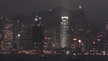Bir VHS kamera kaydı, kapalı gökyüzü altında yüksek binalar, sessiz renkler ve formatın klasik estetik karakteristiğinin hafif ağırlığı ile, Hong Kong 'un kentsel ufuk çizgisini görüntüler.