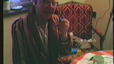 Klasik bir ev videosu, yaşlı bir adamın elinde küçük bir elektronik cihaz tutarak Noel arifesi hediyesi olarak aldığı mutlu ve heyecanlı bir ifadeyle kullanma kılavuzunu okuduğunu gösteriyor.