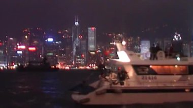 Huzurlu teknelerin Hong Kong 'un karanlık sularında yüzeye yansıyan parıldayan şehir ışıklarıyla hızlı bir şekilde süzülmesi.