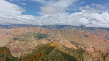 Nepal dağları üzerinde süzülen hava görüntüleri Himalaya dağları, yüksek tepeler ve bulutlu gökyüzünün altında engebeli tepeler