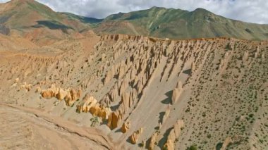Nepal 'in uzak Mustang bölgesindeki eşsiz kaya oluşumlarının ardında yükselen görkemli Nilgiri sıradağlarının çarpıcı manzaraları manzaranın engebeli güzelliğini gözler önüne seriyor.