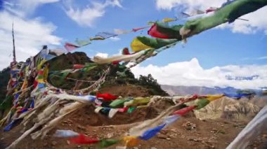 Nepal 'deki Himalayalar' ın nefes kesici arka planına karşı rüzgarda dalgalanan renkli dua bayrakları bölgenin dingin ve ruhani atmosferini yakalıyor.