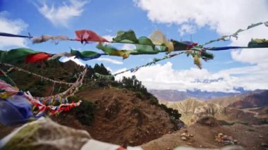 Himalaya dağlarının çarpıcı manzarası rüzgarda hafifçe dalgalanan dua bayraklarıyla doğanın dingin güzelliğini ve ruhani geleneği yakalıyor.