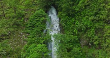 Nepal 'in dingin manzarasının kalbinde şelale çağlayan yemyeşil bir tepe manzarası.