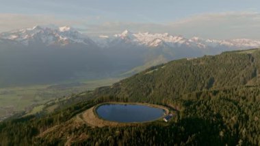 Plettsaukopf Reservoir 'un havadan görünüşü yemyeşil ormanlarla çevrili, karlı dağlar nefes kesen doğal bir zemin oluşturuyor.