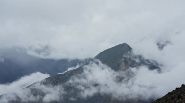 Huşu uyandıran Himalaya sıradağları üzerinde sürüklenen bulutların çarpıcı görüntüsü doğanın elementlerinin dramatik etkileşimini vurgular.