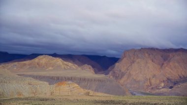 Nepal 'in çöl dağ manzarasının nefes kesici panoramik manzarası, engebeli arazi, kurak yamaçlar ve bulutlu bir gökyüzünün altındaki uzak tepeler