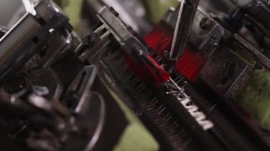 Endüstriyel tekstil üretimine yakın çekim, beyaz iplik iğnelerle besleniyor, makine etkin bir şekilde kumaş dokuyor.