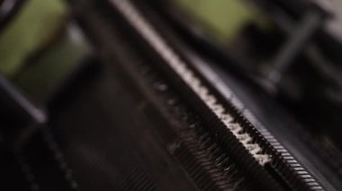 Endüstriyel bir makinedeki hassas örgü işleminin yakından görüntüsü, beyaz iplik ustalıkla kumaşa dokunuyor.