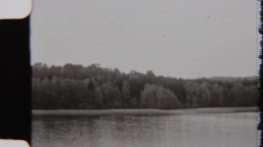 8 mm 'lik film, yemyeşil ağaçlarla çevrili, tek renkli siyah beyaz gölün tarihsel çekiciliğini yakalıyor, zamansız ve sakin doğal bir manzarayı çağrıştırıyor.