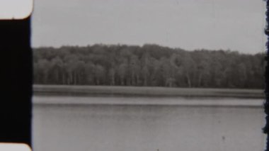 Klasik monokromda sakin bir göl manzarası. Uzakta yemyeşil ağaçlar, zamansız ve sakin bir manzara yakalıyor.