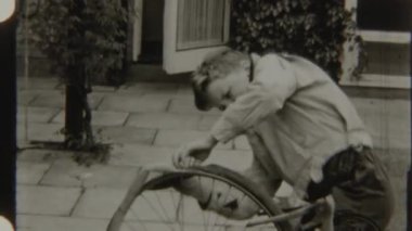 Genç çocuk bisikletinin lastik izlerini dikkatlice inceleyip onarıyor, dışarıda bakım yapıyor.