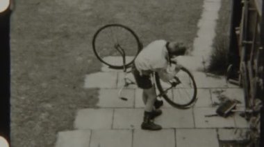 Arka bahçedeki kaldırımda bisiklet lastiklerini inceleyen genç çocuk her şeyin iyi durumda olduğundan emin oluyor.