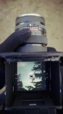 Birinci şahıs görüntüsünden yakalanan bir fotoğrafçı, sakin bir doğa yolunda yürüyor ve huzurlu bir çevreye dikkatle elle objektifle bakıyor.