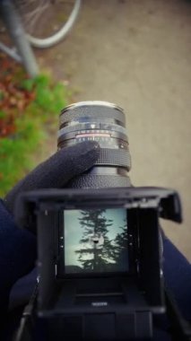 Birinci şahıs görüntüsünden çekilen bir fotoğrafçı, doğanın özünü yakalamak için klasik bir kamera kullanır, zamansız ve bilinçli bir dokunuşla manzaranın ince güzelliğine odaklanır.