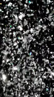 Parlak gümüş konfeti yavaş çekimde zarifçe yere düşüyor. Karanlık bir zemine karşı ışıl ışıl bir şelale oluşturuyor.