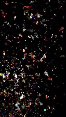 Çok renkli konfeti parçacıklarının canlı bir görüntüsü karanlık bir arkaplanda zarafetle yukarıya doğru sürükleniyor ve neşeli ve büyülü bir atmosfer yaratıyor.